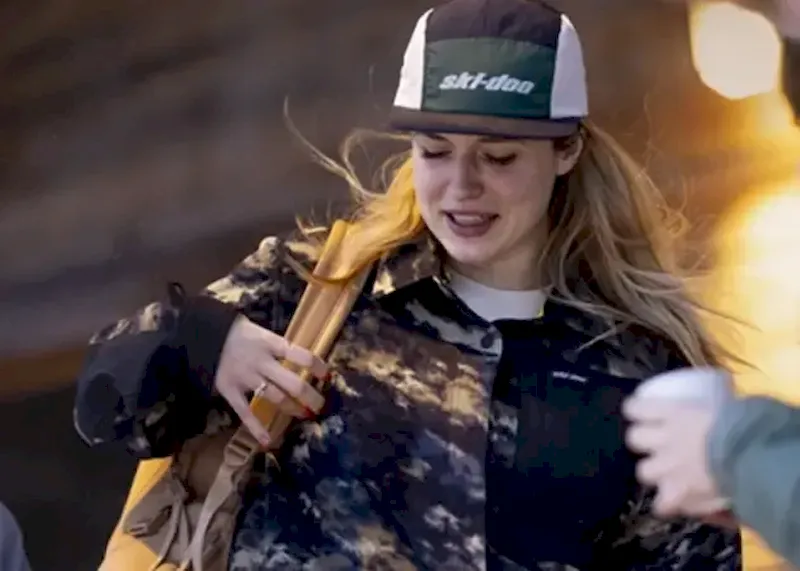 Close-up of a rider wearing a green Ski-Doo hat and winter sports apparel