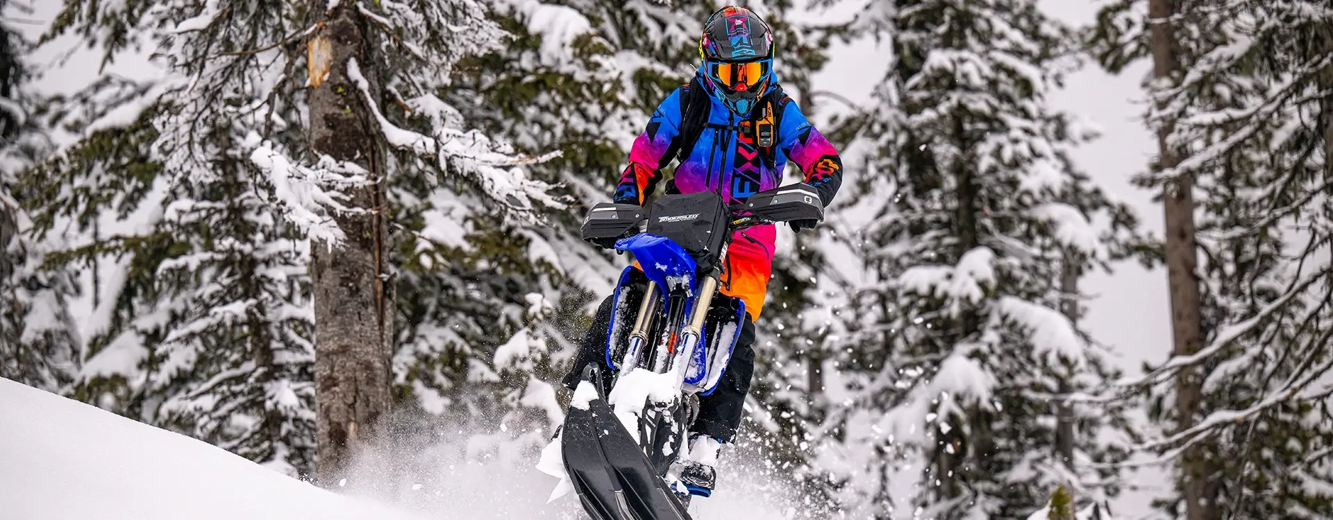 White dirt bike with the new 2025 red and black Timbersled snow bike kit parked in deep mountain snow