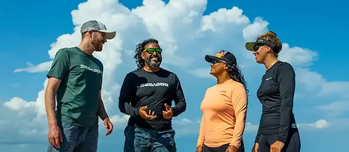Group of people wearing Sea-Doo branded shirts and hats against a blue sky