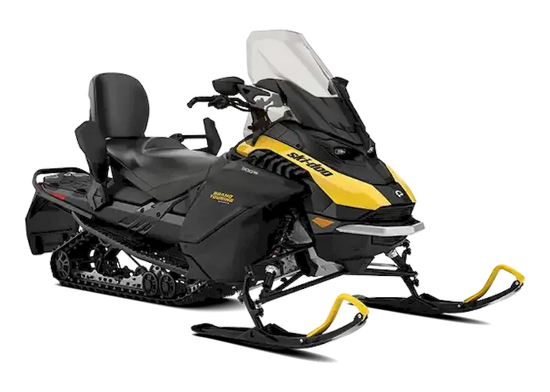 Black Grand Touring snowmobile with yellow accents, passenger seat, and tall clear windshield on a white background