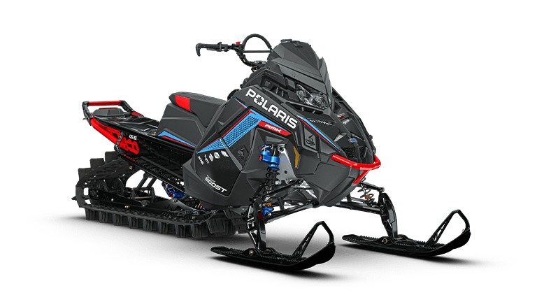 Rider on a blue Polaris RMK Factory Edition towing a cargo sled through snow at sunset
